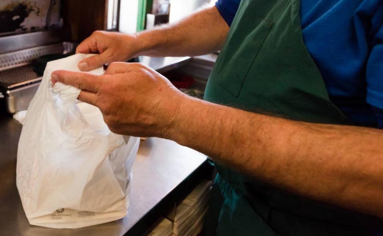 A man bags up a meal from Zeke's